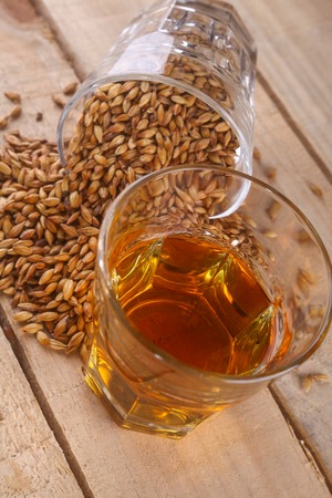 Glass of whiskey and a glass of barley malt on a wooden backgroundの写真素材