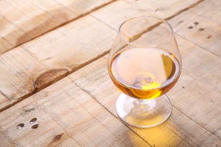 Snifter glass with amber colored brandy on a grunge wooden tableの写真素材