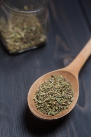 Wooden spoon with green spice on a dark wooden surfaceの写真素材