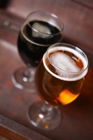Full glass of dark and ligth beer standing in a wooden case