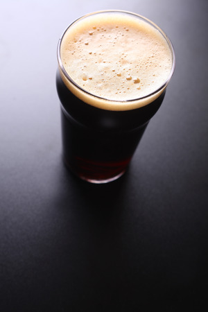 Nonic pint glass of dark ale shot topdown over a dark backgroundの写真素材
