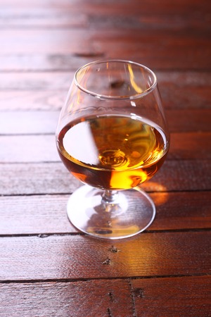Snifter glass full of brandy standing on a wooden table