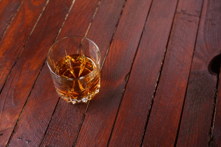 Tumbler glass full of whisky standing on a wooden tableの写真素材