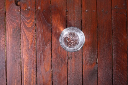 Tall glass full of lightly carbonated drinking water standing on a wooden tableの写真素材