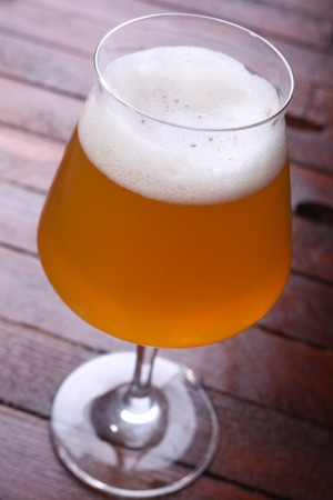 Glass full of unfiltered wheat beer standing on a wooden tableの写真素材