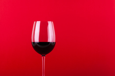 Glass of red wine over a vivid red backgroundの写真素材