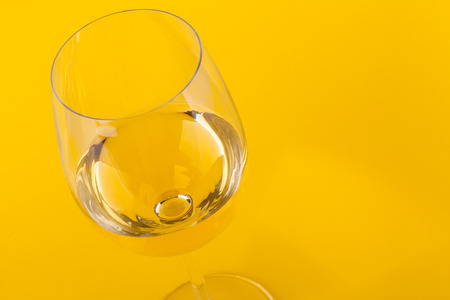 Glass of white wine over a vivid yellow backgroundの写真素材