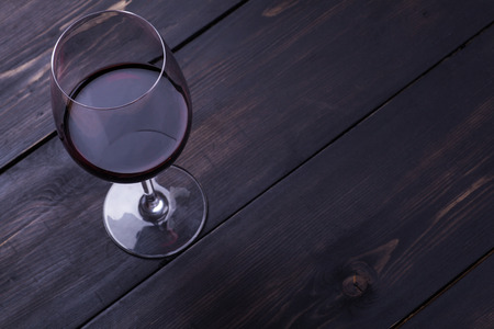 Glass of red wine on a textured dark wood surfaceの写真素材
