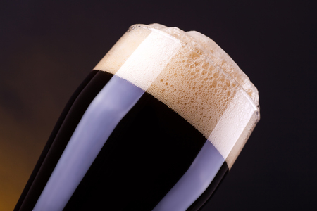 Tall glass full of dark beer over a dark backgroundの写真素材