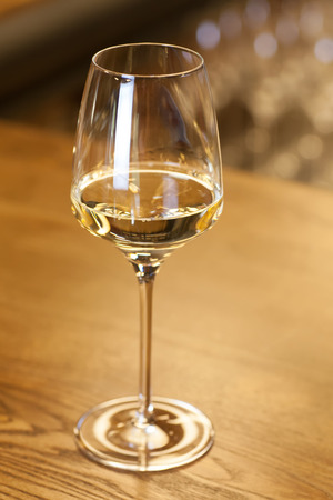 Glass of white wine standing on a bar counter in a fancy wine restaurantの写真素材