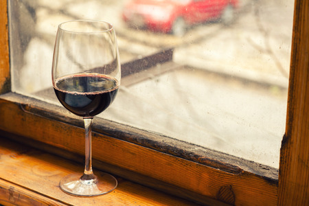 Tall glass of wine on a wood windowsillの写真素材