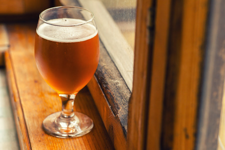 Regular class of amber ale on a wood windowsill