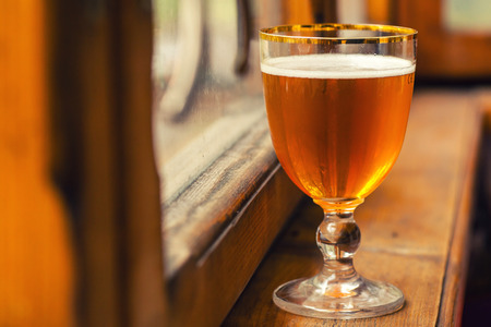 Strong ale in a special glass on a wood windowsillの写真素材