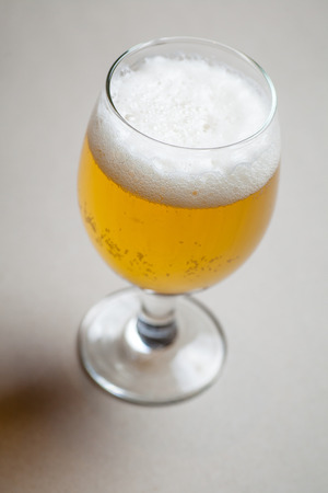 Glass full of light lager beer standing on a gray tableの写真素材
