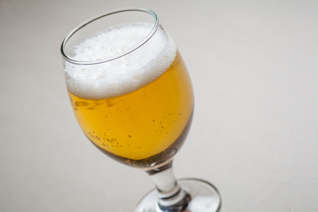 Glass full of light lager beer standing on a gray tableの写真素材