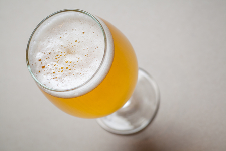 Glass full of light lager beer standing on a gray tableの写真素材