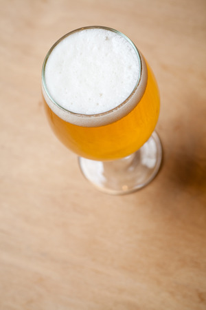 Glass full of light lager beer standing on a textured wooden tableの写真素材