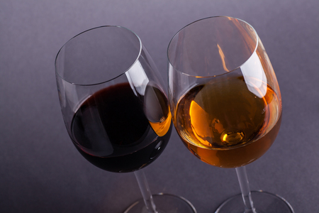 Glass of red and white wine over a dark grey backgroundの写真素材