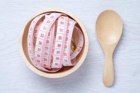 Tape Measure in wooden bowl on the white wooden floor. for someone who want to diet , weight lossの写真素材