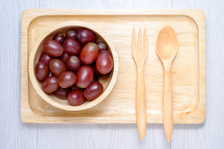 Red grapes in wooden bowl and spoon. they on white wooden table. Clear lightの写真素材