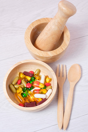 medicine and vitamin on wooden bowl with wooden spoon, fork and mortarの写真素材