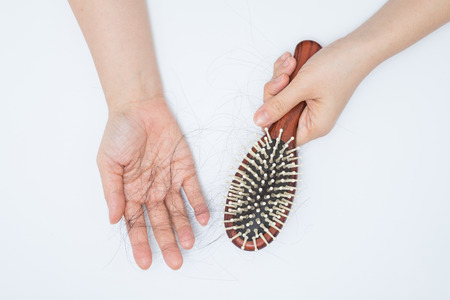 Hair loss in woman hands and bruch, on white background, women postpartum defluviumの写真素材