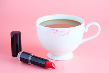 red lipstick and cup of coffee on pink backgroundの写真素材