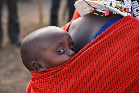 Very young child from Masai tribe in the Ngorongoro reserve in Tanzania on the back of his motherのeditorial素材