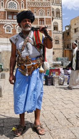 Unidentified old man shown in the capital of Yemen Sanaa on March 6, 2010. Armed man in traditional costume with typical arme blanche jambia stands with ancient rifle on the street.のeditorial素材