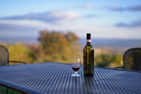Glass of red wine and empty bottle on the table at morning time early fall  Tuscan, Italyの写真素材
