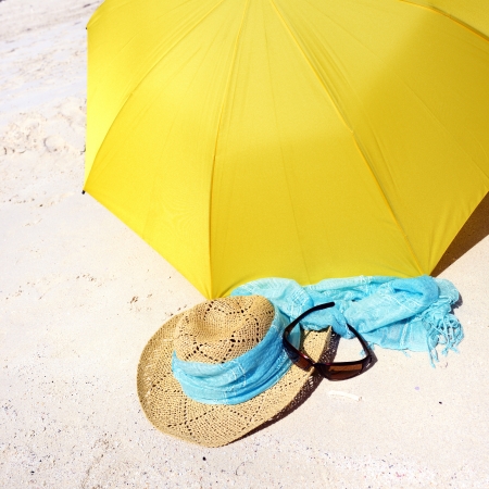 Bright yellow umbrella, hat and sunglass on the sandy beach. Summer conceptの写真素材