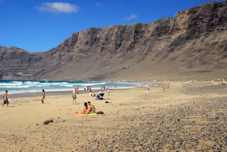 LANZAROTE, PLAYA FAMARA, SPAIN - JUN 21 2008  Sandy beach Playa Famara in Canarian island, Lanzarote, Spain  Tourists on the most popular beach at the island of Lanzaroteのeditorial素材