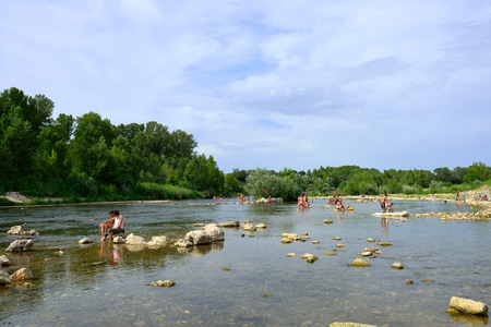 REMOULINS, FRANCE - JUL 19, 2014  Tourists have a rest on the shore of Gardon river in southern France  The Gorge du Gardon is a popular recreation area for kayaking, canoeing, rock climbing, and hikingのeditorial素材