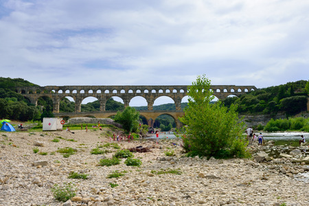 REMOULINS, FRANCE - JUL 19, 2014: Tourists have a rest on the shore of Gardon river under an old Roman aqueduct Pont du Gard. The Gorge du Gardon is a popular recreation area for kayaking, canoeing and hikingのeditorial素材