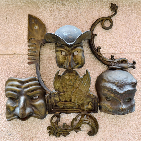 Ancient bronze sculpture on a wall medieval house as symbol of Venice - gondola, carnival mask and winged venetian lion, Venice, Italyのeditorial素材