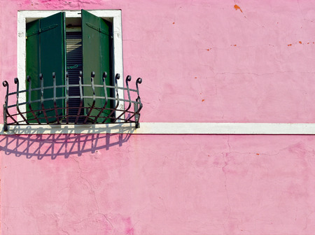 Burano island, Venice. Closed window with green shutter on rose wall.  Colorful houses island and landmark of Veneto region, Italyの写真素材