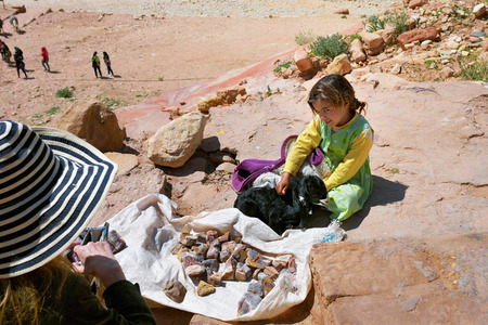 PETRA, JORDAN - APR1, 2015: little Jordanian girl with her lamb sells local stones in Petra. Jordanian children from an early age accustomed to the workのeditorial素材