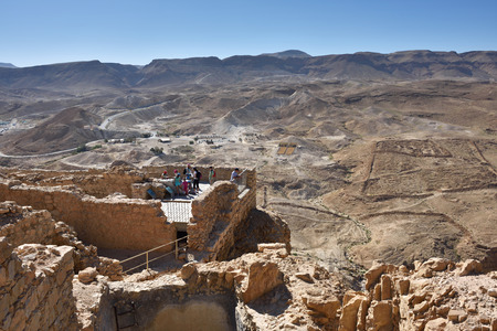MASADA, ISRAEL - APR 5, 2015: Tourists visit the ruins of the zealot fortress Masada, the ancient roman military camp on background. Judean desert, Israelのeditorial素材