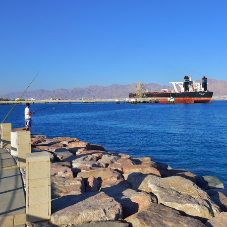 EILAT, ISRAEL - MARCH 31, 2015: Fisherman in harbor of Eilat, Vessel Genmar Vision moored at...