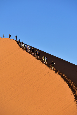 SOSSUSVLEI, NAMIBIA - JAN 29, 2016: Tourists climb Dune No.45 in a year that was declared as a drought year by the government in Namibia, Africaのeditorial素材