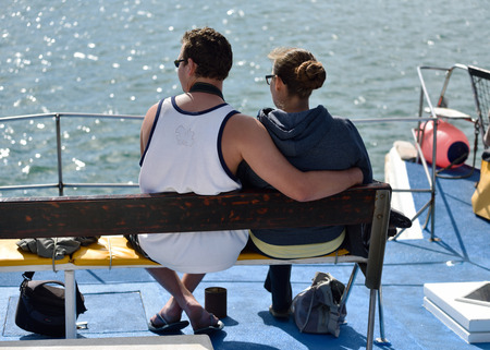 LUDERITZ, NAMIBIA - JAN 27, 2016: Young couple of tourist on the boat during excursion trip to the penguin island in gulf of Luderitz. Such activity is very popular tourist attraction to see african penguinsのeditorial素材