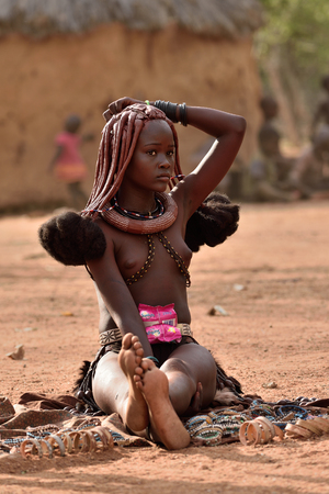 KAMANJAB, NAMIBIA - FEB 1, 2016: Young unidentified Himba woman with the typical necklace and hairstyle shown in himba tribe villageのeditorial素材