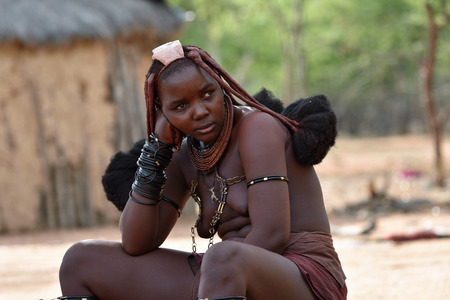 KAMANJAB, NAMIBIA - FEB 1, 2016: Young unidentified Himba woman with the typical necklace and hairstyle shown in himba tribe villageのeditorial素材