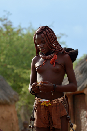 KAMANJAB, NAMIBIA - FEB 1, 2016: Unidentified Himba woman with the typical necklace and hairstyle shown in himba tribe villageのeditorial素材