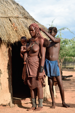 KAMANJAB, NAMIBIA - FEB 1, 2016: Unidentified Himba women and child with the typical necklace and hairstyle shown in himba tribe villageのeditorial素材