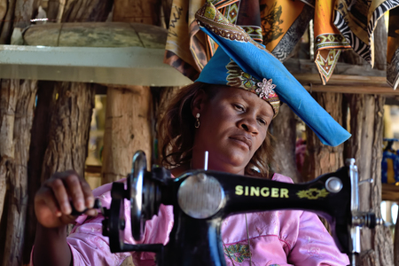 KAOKOLAND, NAMIBIA - FEB 1, 2016: Unidentified Herero Woman in traditional clothes with sewing machine. The Herero belonging to the Bantu group, with about 240,000 members alive today.のeditorial素材