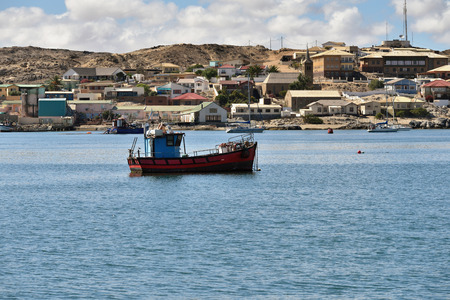 LUDERITZ, NAMIBIA - JAN 27, 2016: A little fishing trawler in Luderitz bay at sunrise. The fishing industry is one of the most important sectors of the Namibian economyのeditorial素材