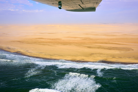 Flight over the Sceleton coast in Namibia where dunes of the Namib desert meet with Atlantic ocean, Africaの写真素材