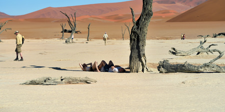 DEADVLEI, NAMIBIA - JAN 29, 2016: Tourists have a rest in shadow of the dead camelthorn tree in Deadvlei, Sossusvlei. Namib-Naukluft National Park, Namibia, Africaのeditorial素材