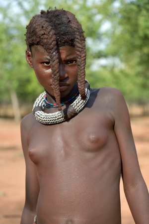 KAMANJAB, NAMIBIA - FEB 1, 2016: Young unidentified Himba girl with the typical necklace and double plait hairstyle of the pre-adolescentのeditorial素材